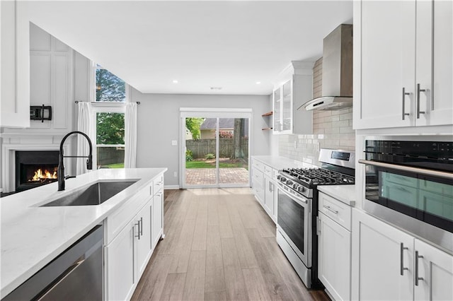 615 Rosedown Way, Alpharetta, GA 30022 - kitchen with appliances with stainless steel finishes, wall chimney exhaust hood, light wood-style flooring, backsplash, and white cabinets