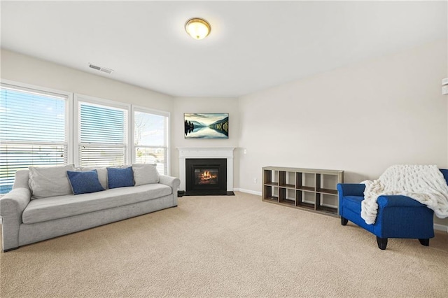 living area with carpet floors, a fireplace with flush hearth, visible vents, and baseboards