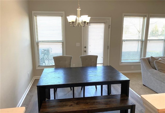 dining area with hardwood / wood-style flooring, an inviting chandelier, and plenty of natural light