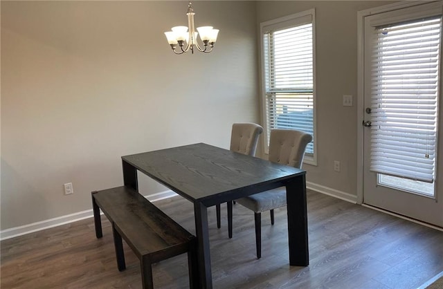 dining room with a notable chandelier, a healthy amount of sunlight, and dark wood-type flooring