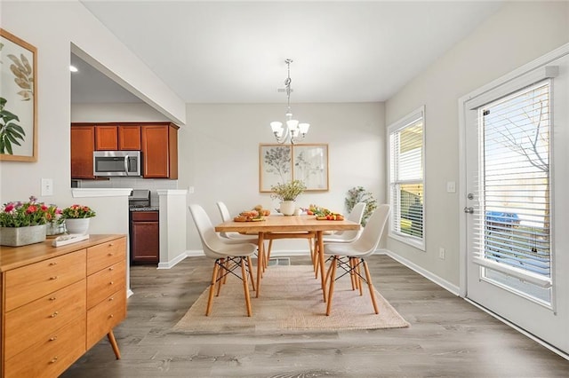 dining room with baseboards, light wood-type flooring, and an inviting chandelier