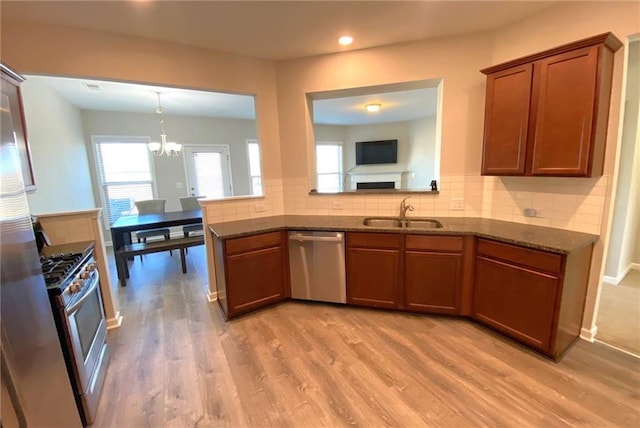 kitchen with sink, stainless steel appliances, an inviting chandelier, backsplash, and light wood-type flooring