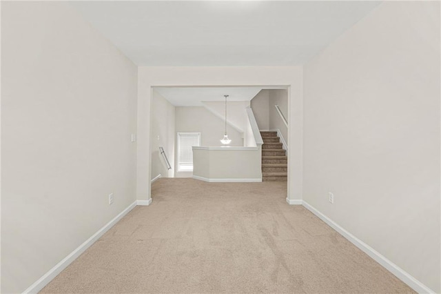 spare room featuring baseboards and light colored carpet