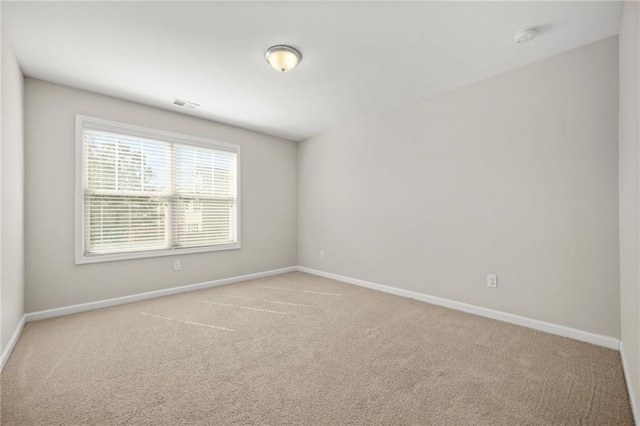 unfurnished room with carpet flooring, visible vents, and baseboards