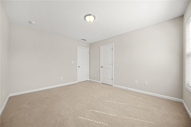 empty room featuring a healthy amount of sunlight, carpet, visible vents, and baseboards