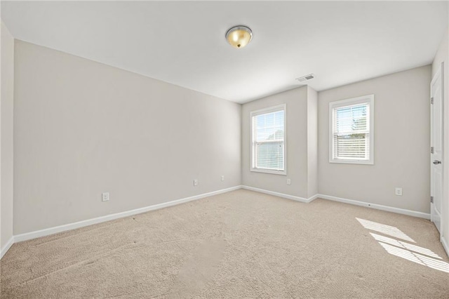 unfurnished room featuring light carpet, visible vents, and baseboards