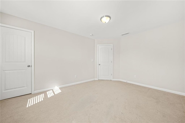 empty room featuring baseboards, visible vents, and light colored carpet