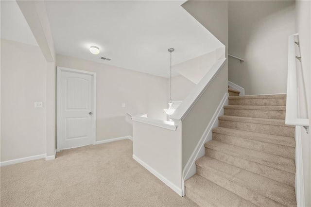 staircase featuring visible vents, baseboards, and carpet flooring