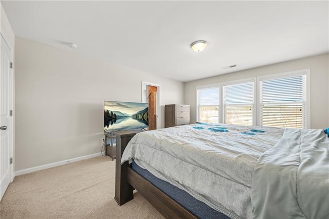 bedroom featuring light carpet, a spacious closet, visible vents, and baseboards