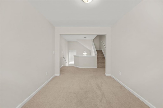 interior space featuring stairs, baseboards, and light colored carpet