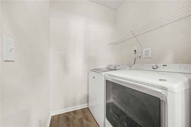 laundry area featuring laundry area, separate washer and dryer, dark wood-type flooring, and baseboards
