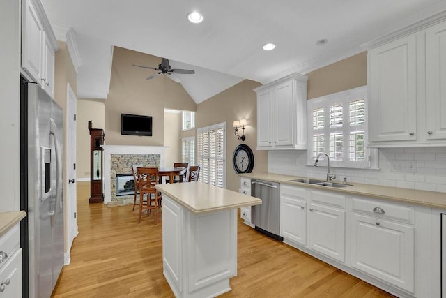 kitchen with white cabinets, ceiling fan, a sink, stainless steel appliances, and backsplash