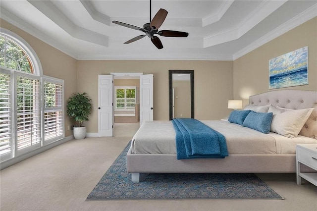 bedroom with carpet floors, ornamental molding, a ceiling fan, and a tray ceiling