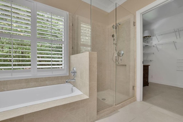 full bathroom featuring a walk in closet, tile patterned flooring, a shower stall, ornamental molding, and a bath