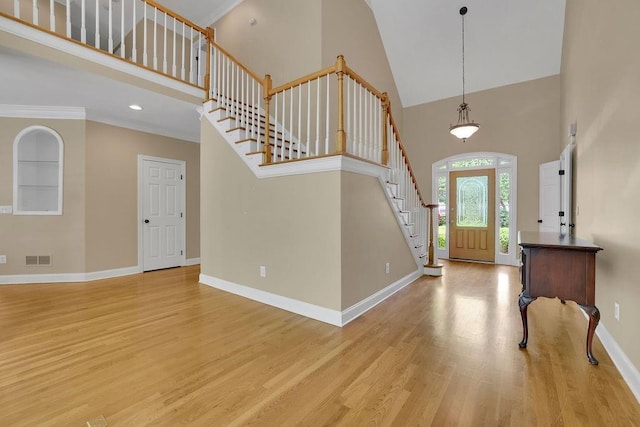 entrance foyer featuring visible vents, wood finished floors, high vaulted ceiling, baseboards, and stairs