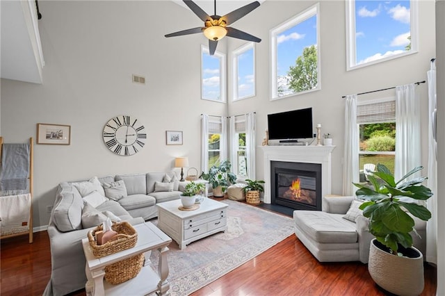 121 Bradshaw Park Dr, Woodstock, GA 30188 - living room featuring a towering ceiling, ceiling fan, wood finished floors, and a glass covered fireplace