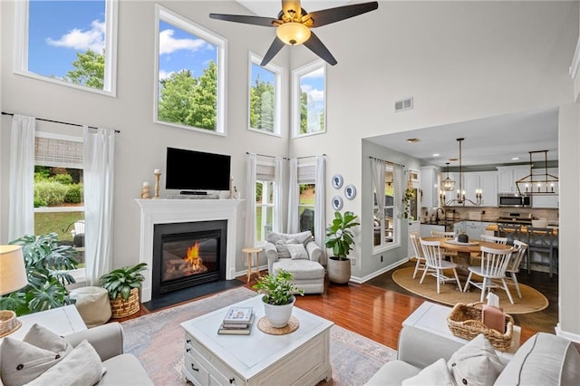 121 Bradshaw Park Dr, Woodstock, GA 30188 - living room featuring healthy amount of natural light, ceiling fan, a fireplace with flush hearth, a towering ceiling, and dark wood-style flooring