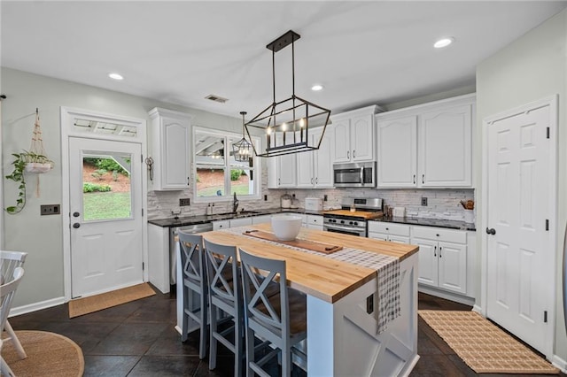 121 Bradshaw Park Dr, Woodstock, GA 30188 - kitchen featuring appliances with stainless steel finishes, white cabinetry, a sink, a kitchen bar, and recessed lighting