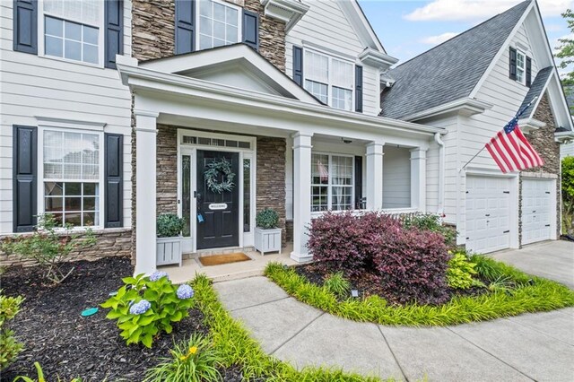 121 Bradshaw Park Dr, Woodstock, GA 30188 - view of exterior entry featuring stone siding, concrete driveway, and a porch