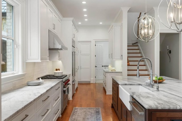 kitchen featuring white cabinetry, stainless steel appliances, decorative light fixtures, and sink