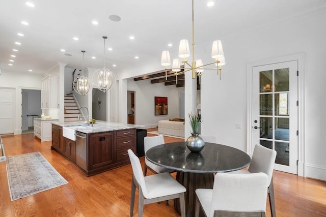 dining space featuring beam ceiling, a chandelier, sink, and light wood-type flooring