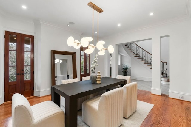 dining room with french doors, a notable chandelier, crown molding, and light wood-type flooring