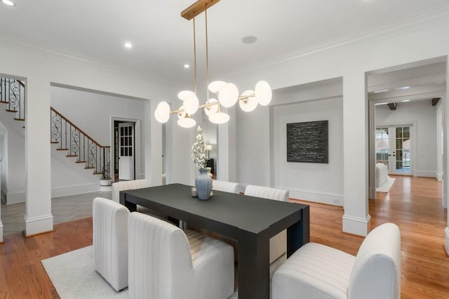 dining room featuring decorative columns, a chandelier, ornamental molding, light wood-type flooring, and french doors