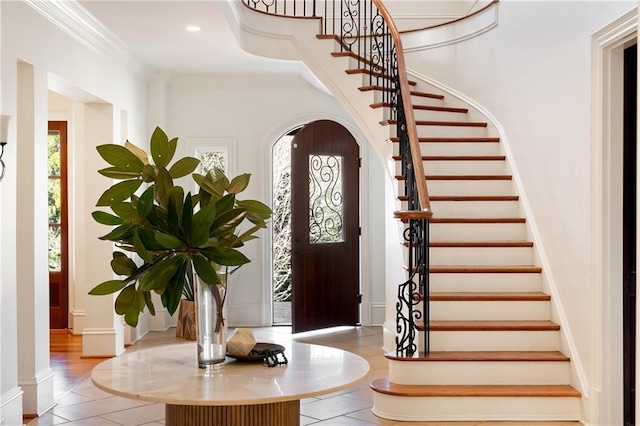 foyer entrance with light tile patterned flooring and crown molding