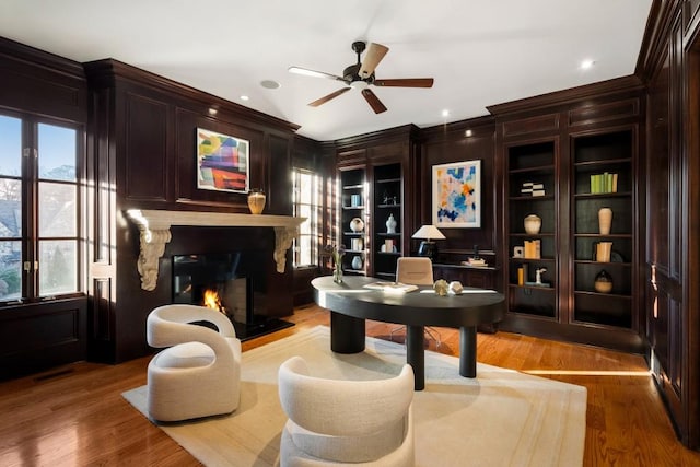 living area featuring ceiling fan, hardwood / wood-style flooring, and built in shelves