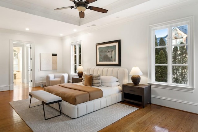 bedroom with ensuite bathroom, ornamental molding, ceiling fan, a raised ceiling, and light hardwood / wood-style flooring