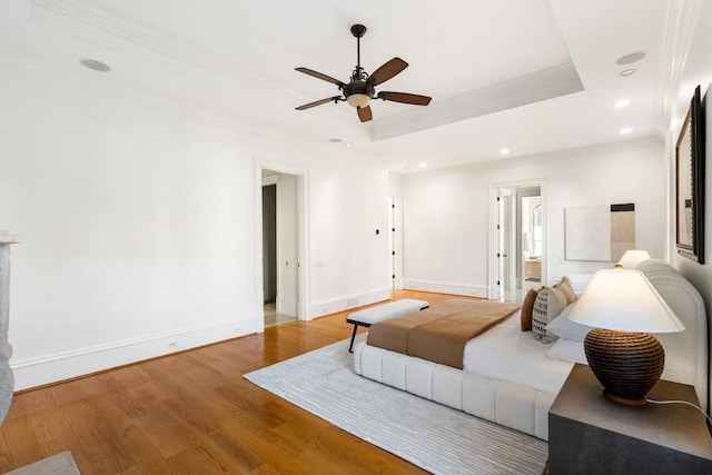 bedroom with a raised ceiling, wood-type flooring, ornamental molding, and ceiling fan