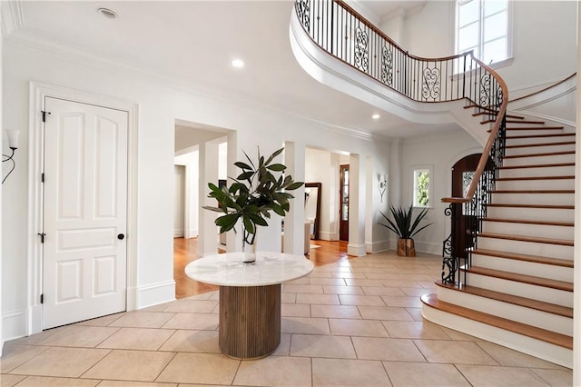 tiled foyer with a towering ceiling and crown molding