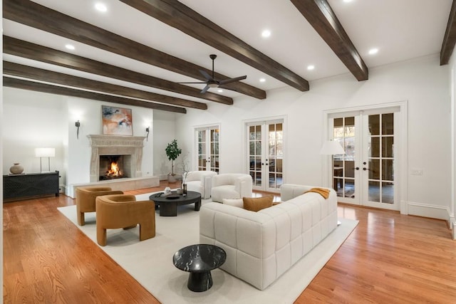 living room with ceiling fan, light hardwood / wood-style flooring, beam ceiling, and french doors