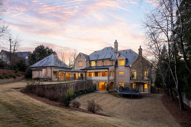 back house at dusk with a yard and a trampoline