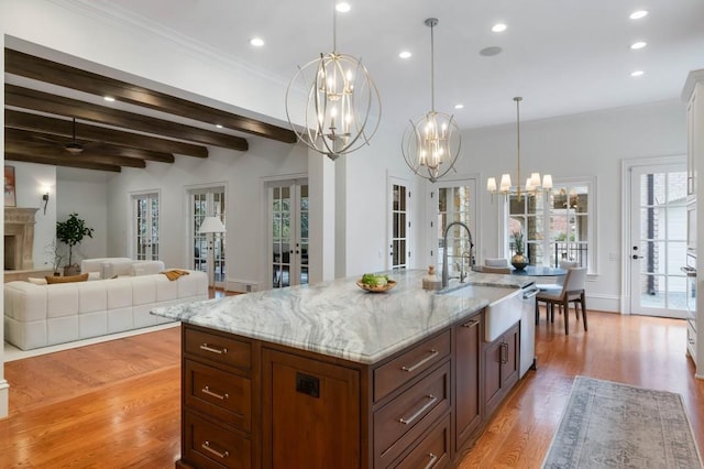 kitchen with french doors, hanging light fixtures, an island with sink, a notable chandelier, and beamed ceiling