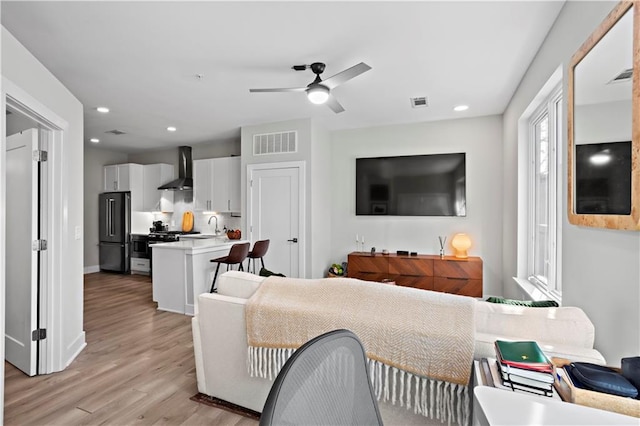 living room with ceiling fan, sink, and light wood-type flooring