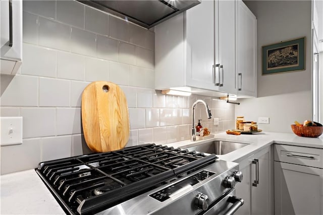 kitchen with tasteful backsplash, sink, stainless steel range, and ventilation hood