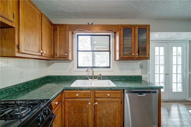 kitchen with stainless steel dishwasher, a healthy amount of sunlight, french doors, and sink