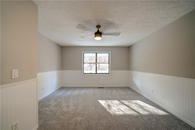 carpeted empty room featuring ceiling fan and a textured ceiling