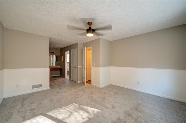 unfurnished room featuring ceiling fan, light carpet, and a textured ceiling