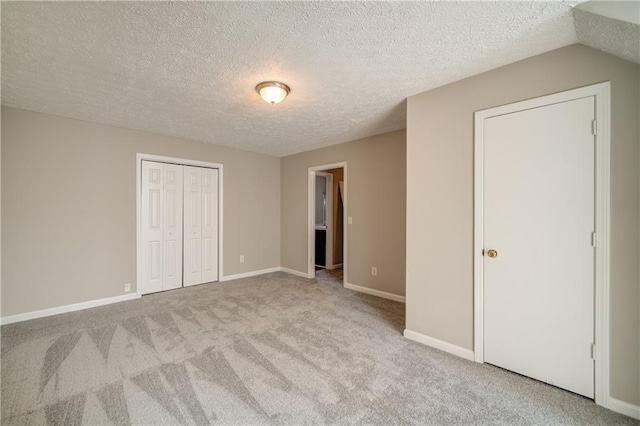 unfurnished bedroom featuring light colored carpet, a closet, and a textured ceiling