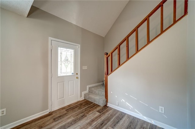 foyer entrance with vaulted ceiling and hardwood / wood-style flooring