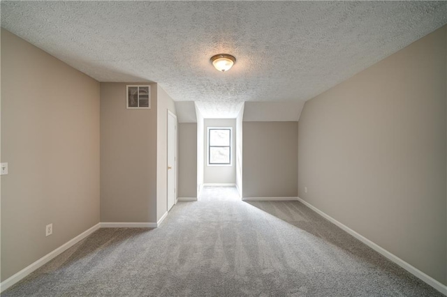 carpeted spare room featuring a textured ceiling and lofted ceiling