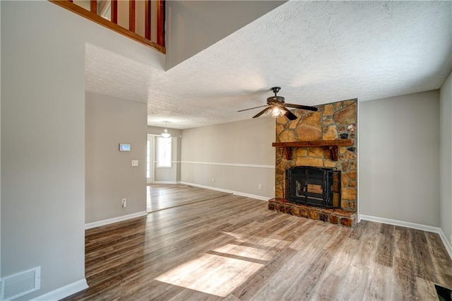 unfurnished living room with a textured ceiling, ceiling fan, a fireplace, and hardwood / wood-style flooring