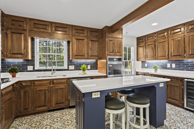 kitchen featuring sink, a kitchen bar, a center island, stainless steel appliances, and beverage cooler