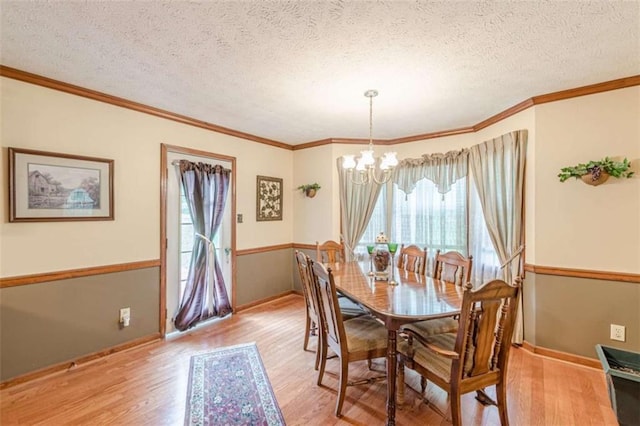 4411 Westerling Ct, Powder Springs, GA 30127 - dining area featuring light wood-style flooring, a chandelier, a textured ceiling, and ornamental molding