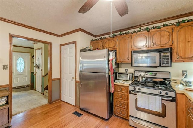 4411 Westerling Ct, Powder Springs, GA 30127 - kitchen with appliances with stainless steel finishes, light wood-type flooring, brown cabinets, a textured ceiling, and ornamental molding