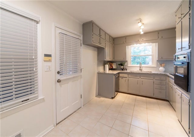 kitchen featuring gray cabinetry, black oven, a sink, and decorative backsplash