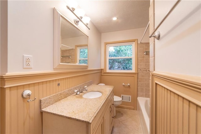 bathroom with visible vents, wainscoting, toilet, tile patterned flooring, and vanity