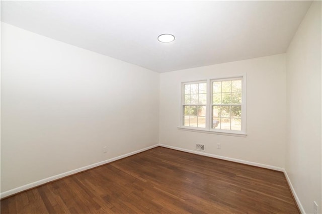 unfurnished room with baseboards and dark wood-style flooring